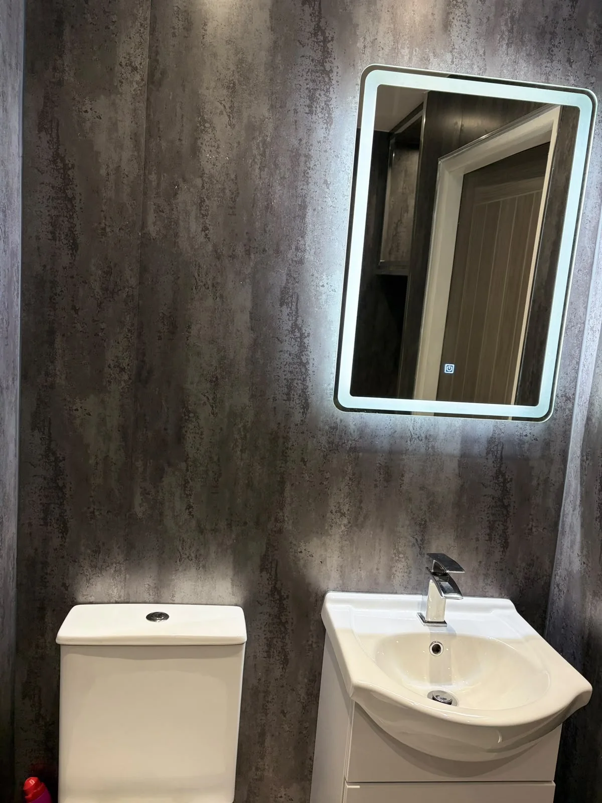 Dark contemporary bathroom toilet and illuminated mirror