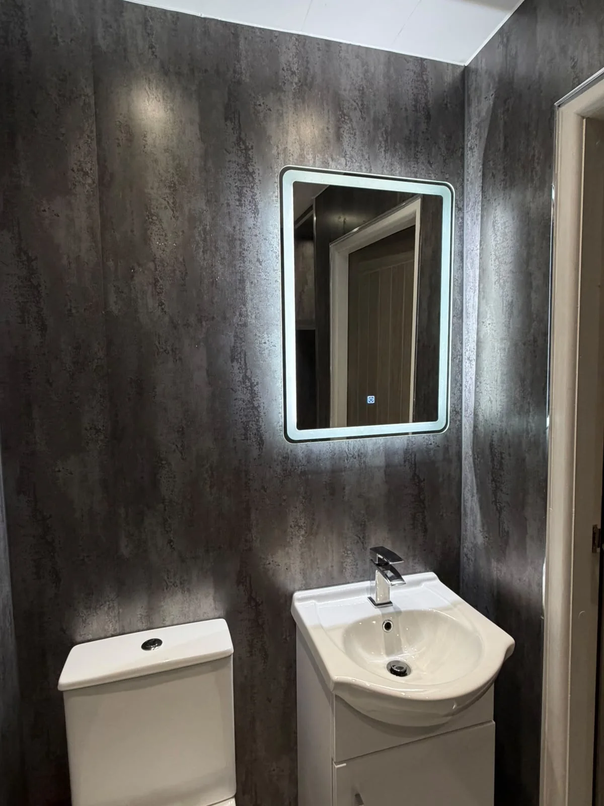 Bathroom basin, toilet and illuminated mirror installation